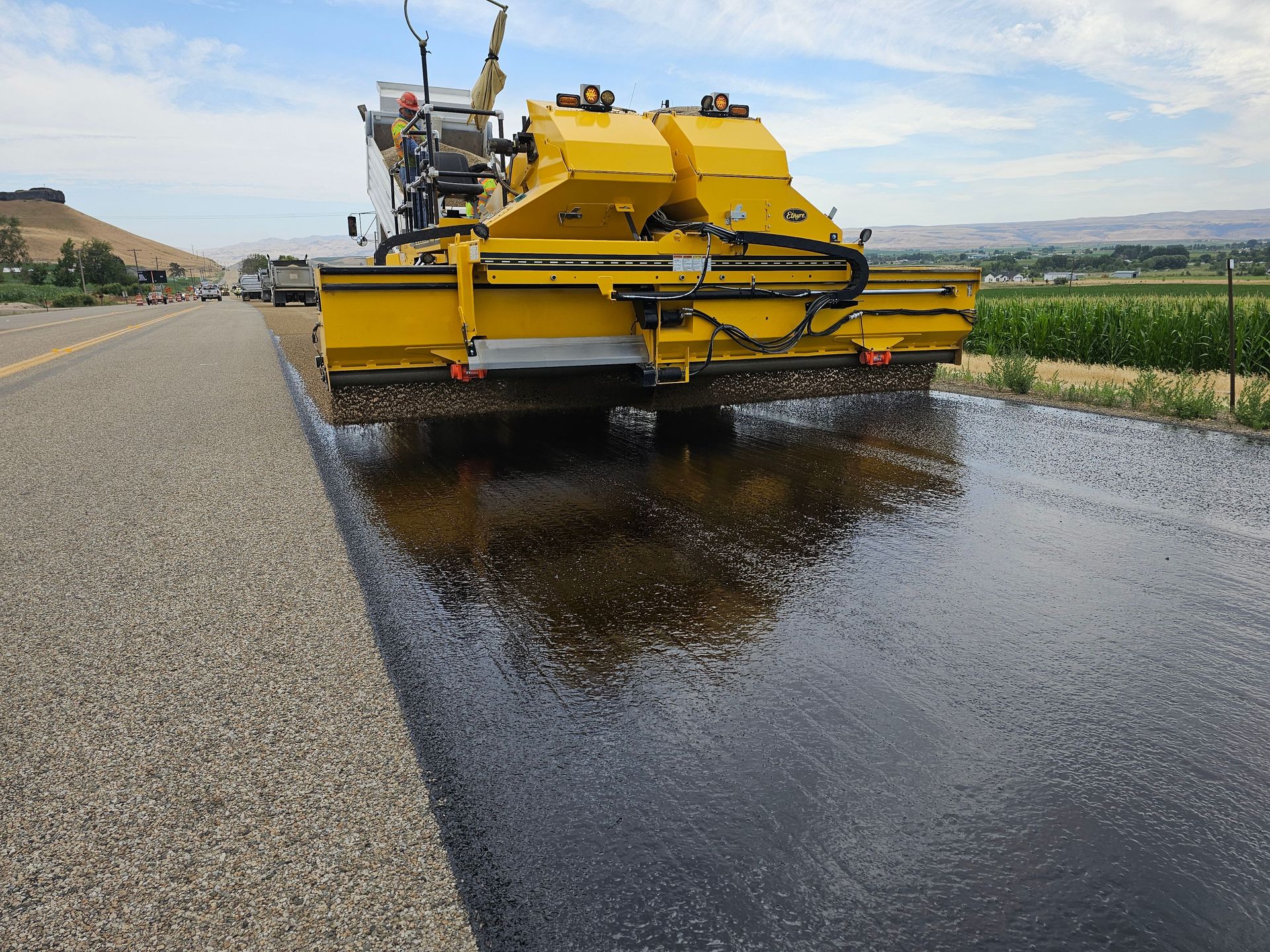 Yellow road construction machine applying asphalt on a rural road in Marsing, Idaho.